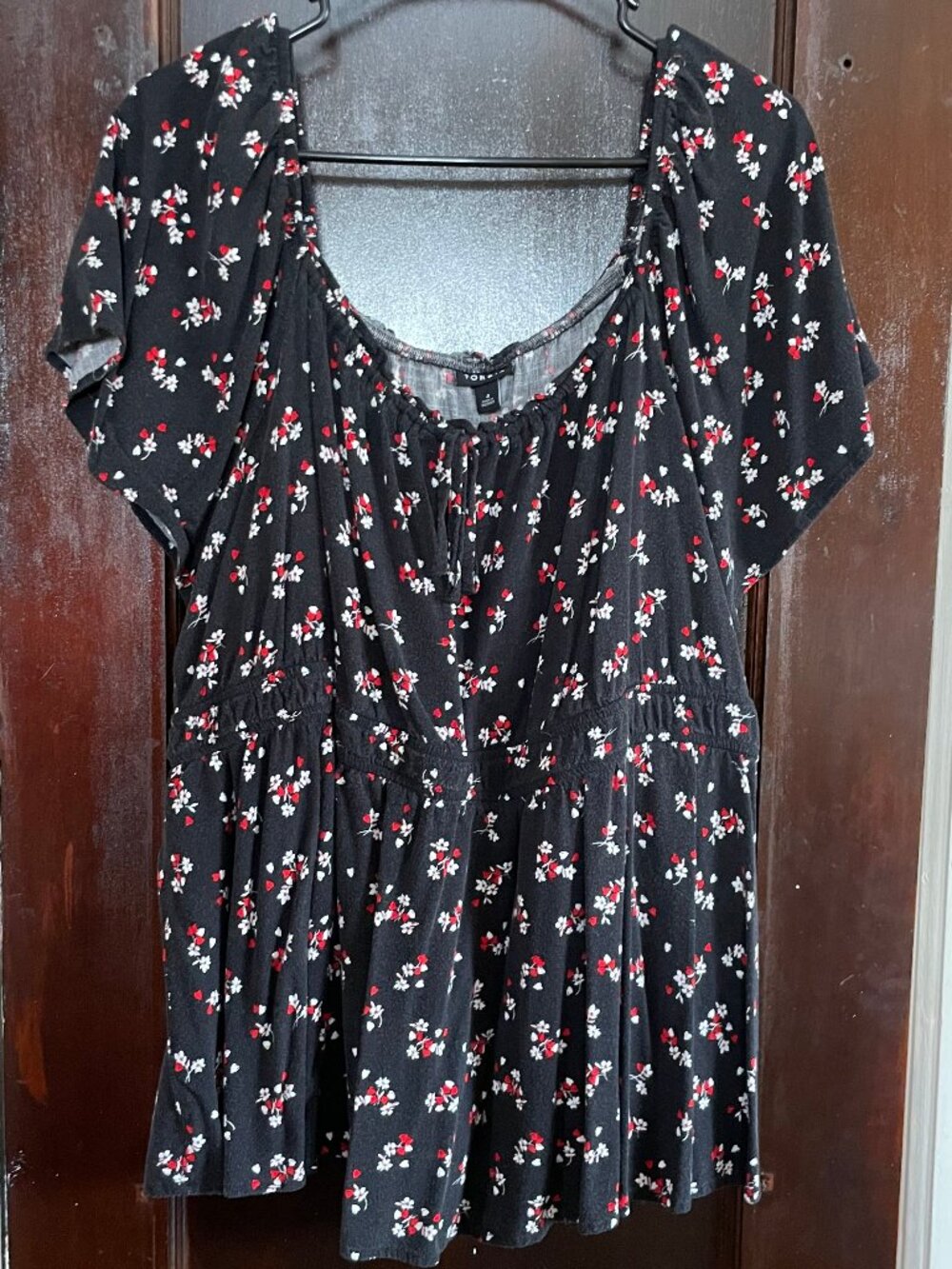 Babydoll peplum top with flutter sleeves, black with red and white flowers